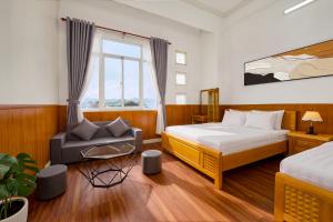 a bedroom with a bed and a chair and a window at Eluna Lilly Da Lat Hotel in Da Lat +20 photos