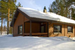 a wooden cabin with snow on the roof at Lomaniini in Tahkovuori