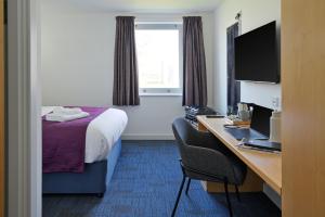 a hotel room with a bed and a desk with a computer at Fire Service College in Moreton in Marsh
