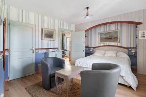 a bedroom with a bed and two chairs and a table at Le Logis des Douves in Tiffauges