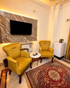 a living room with two chairs and a tv at The Eastern Lodge in Islamabad