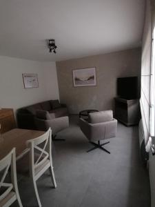 a living room with a couch and chairs and a television at Marisol in Bredene
