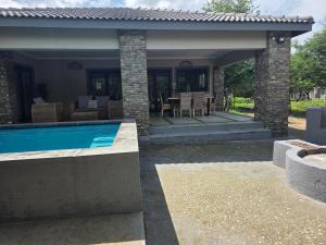 a house with a swimming pool and a patio at Taíta Lodge in Marloth Park
