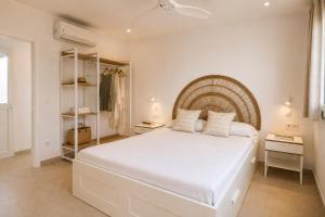a white bedroom with a large white bed with two pillows at Hermosa casa con piscina cerca de la playa de Punta Prima in Punta Prima
