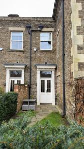 a brick building with a white door and a bench at Rutland Home in Langham