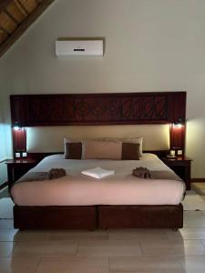 a bedroom with a large bed with a book on it at Ekori Lodge in Mamuno