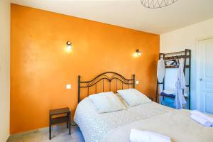 a bedroom with a bed with an orange wall at Studio Le Jardin in Lison