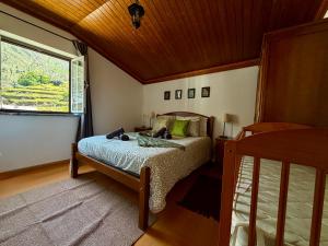 a bedroom with a bed and a window at Égua Nature House in Piódão