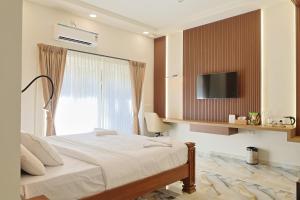 a bedroom with a bed with a tv on the wall at MHOMES Resort - Madurai in Alagar Kovil