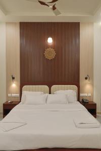 a bedroom with a large bed with white sheets at MHOMES Resort - Madurai in Alagar Kovil