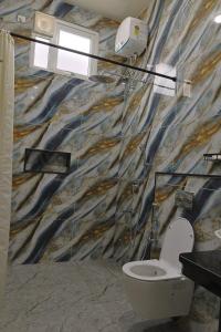 a bathroom with a toilet and a marble wall at MHOMES Resort - Madurai in Alagar Kovil +67 photos