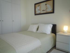 1 dormitorio con 1 cama con lámpara y una foto en la pared en Casa Mar, en Costa da Caparica