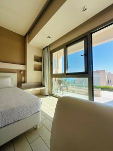 a bedroom with a bed and a large window at Saradari Beach Hotel - Adults Only in Hersonissos