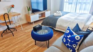 a bedroom with a bed and a desk and a couch at Sidihome 365 Apartment in Osaka
