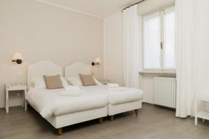 a white bedroom with a white bed and a window at Villa Telli in Garda