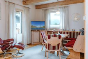 a living room with a table and chairs and a television at Appartement Lackner TOP 2 - Weissensee in Weissensee