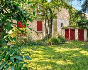 a building with red doors and a grass yard at Petite rivière in Nantes