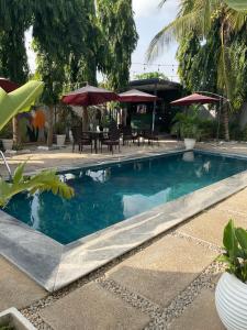 a pool with tables and chairs and umbrellas at Roseann Gold Boutique Hotel in Kusafe