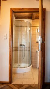 a shower with a glass door in a bathroom at Domek na Modyni, Dwa domki z ruską balią i sauną in Łącko