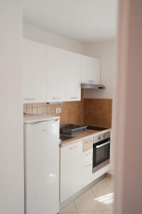 a kitchen with white cabinets and a white refrigerator at Oaza in Nerezine +16 photos