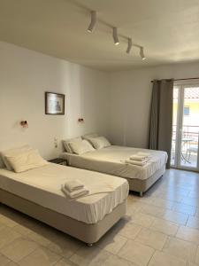 two beds in a room with a balcony at Gardenia studios in Nydri