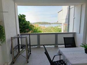 a balcony with a table and chairs and a large window at APARTMAN I SOBE MARIJANA in Rab