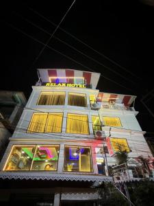 a tall white building with yellow windows at night at Relax Hotel in Bāghdogra