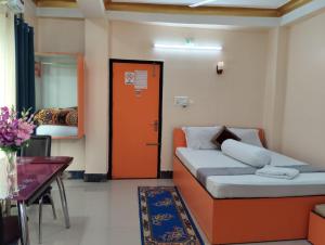 a bedroom with a bed and a table and a door at Relax Hotel in Bāghdogra