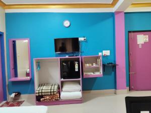 a room with blue and purple walls and a tv at Relax Hotel in Bāghdogra