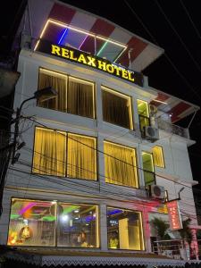 a hotel with a neon sign on top of it at Relax Hotel in Bāghdogra +7 photos