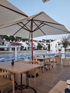 a group of tables with an umbrella next to a pool at Posidonia -Son Bou Apartment in Son Bou