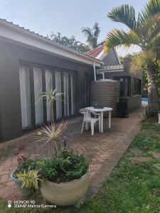 a patio with a table and a table and a house at Cozy Cork Cottage - Sleeps 4 in Beacon Bay