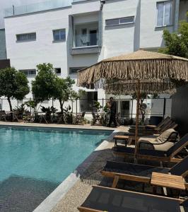 a pool with chairs and an umbrella next to a building at Sunflower Hotel Apartments in Larnaca