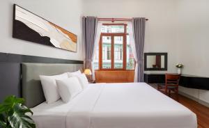 a bedroom with a large white bed and a window at Grand Center Da Lat by Lilly Hotel in Da Lat