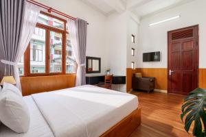 a bedroom with a bed and a desk and a television at Grand Center Da Lat by Lilly Hotel in Da Lat