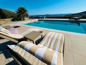 two lounge chairs sitting next to a swimming pool at ELIA PRIVILEGED SUITES Andros ΑΝΔΡΟΣ in Andros