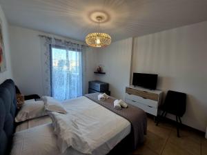 a bedroom with a bed and a television and a chandelier at T2 de standing front de mer in Propriano