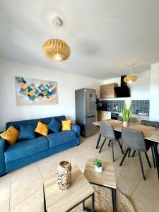 a living room with a blue couch and a kitchen at T2 de standing front de mer in Propriano