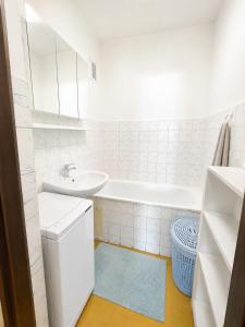 a white bathroom with a sink and a tub at Apartman Anna in Závada