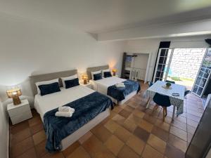 a hotel room with two beds and a table with a table at Alforra Residence 2-Centro-Praias-Levadas in Câmara de Lobos