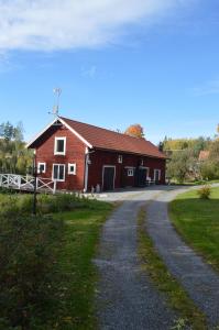 a red barn with a gravel road in front of it at Ekengård in Köping