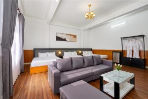 a living room with a couch and a bed at Grand Center Da Lat by Lilly Hotel in Da Lat