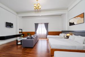 a living room with two beds and a couch at Grand Center Da Lat by Lilly Hotel in Da Lat