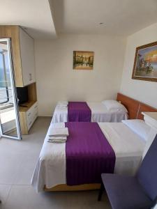 a hotel room with two beds with purple sheets at Sea & Relax Villa in Sarandë