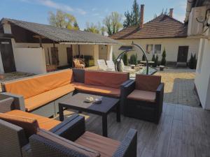 a patio with a couch and chairs and a table at Gém Home Vendégház in Bodony