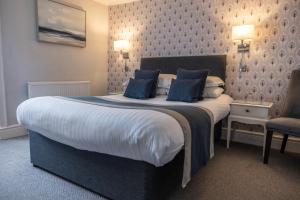 a bedroom with a large bed with blue pillows at Allerdale Court Hotel in Cockermouth
