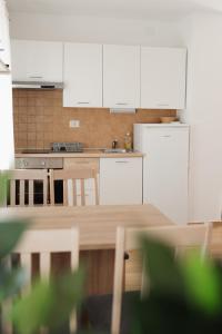 a kitchen with white cabinets and a wooden table at LAVANDLA in Nerezine