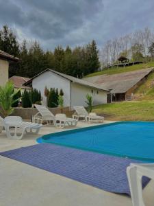 a swimming pool with white chairs and a blue pool at Gém Home Vendégház in Bodony