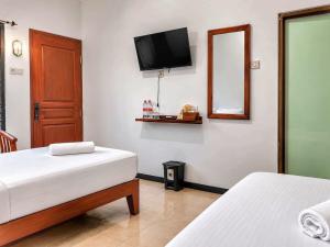 a bedroom with two beds and a television on the wall at Bawangan Express in Ngadisari +5 photos