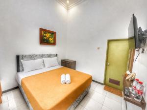 a bedroom with a bed with two slippers on it at Bawangan Express in Ngadisari